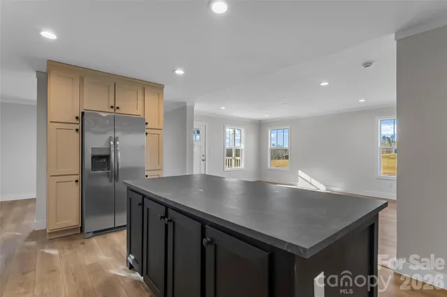 a view of kitchen island a sink wooden floor and a refrigerator