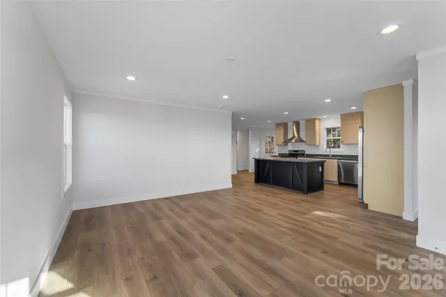 a view of kitchen with kitchen island a sink wooden floor and a refrigerator