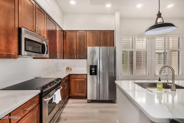 a kitchen with stainless steel appliances granite countertop a refrigerator a stove and a sink with wooden floor