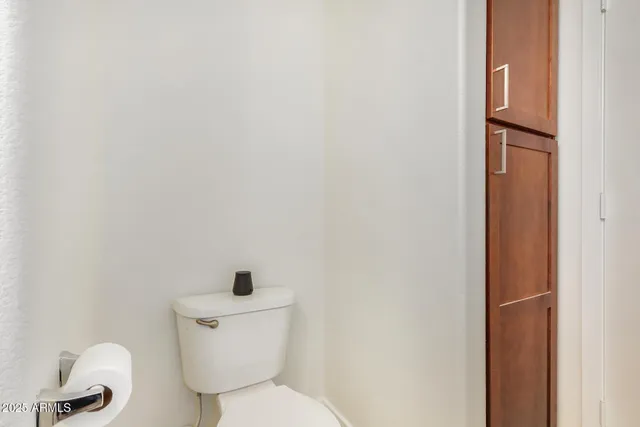 a white toilet sitting next to a white wall