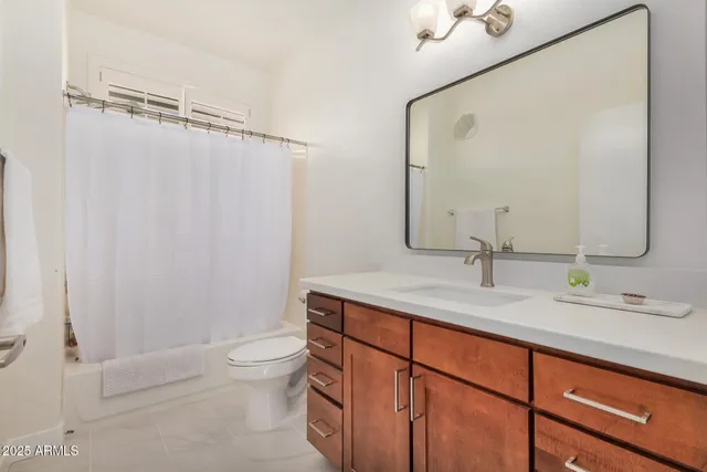 a bathroom with a granite countertop sink a toilet and a mirror