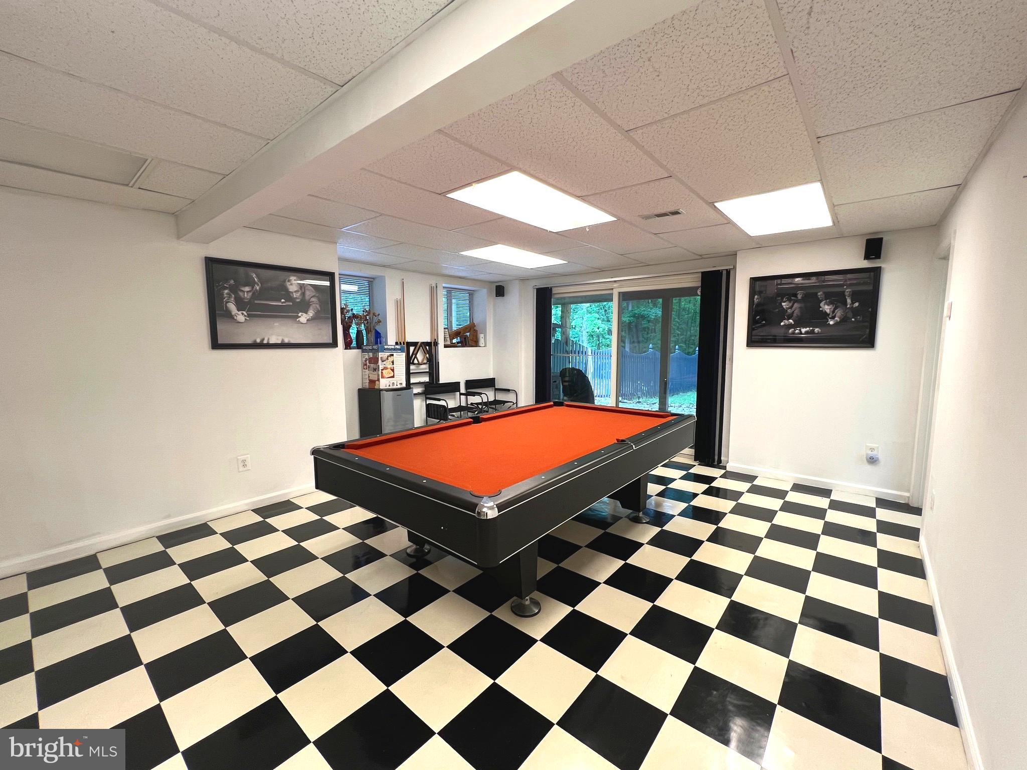 6450 Meadowlark Drive Dunkirk, MD 20754 - Photo 19 of 36 a room with a black white checkered floor with a gaming machine and dining chairs