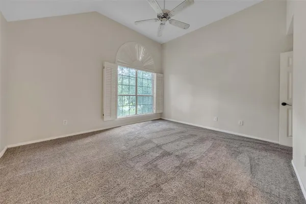 an empty room with a chandelier fan and windows