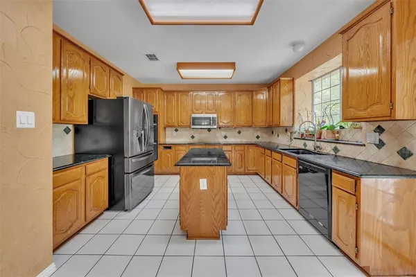 a kitchen with stainless steel appliances granite countertop a refrigerator a sink a stove top oven and a refrigerator