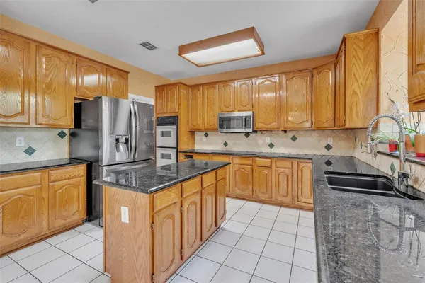 a kitchen with stainless steel appliances granite countertop a sink counter space cabinets and a stove