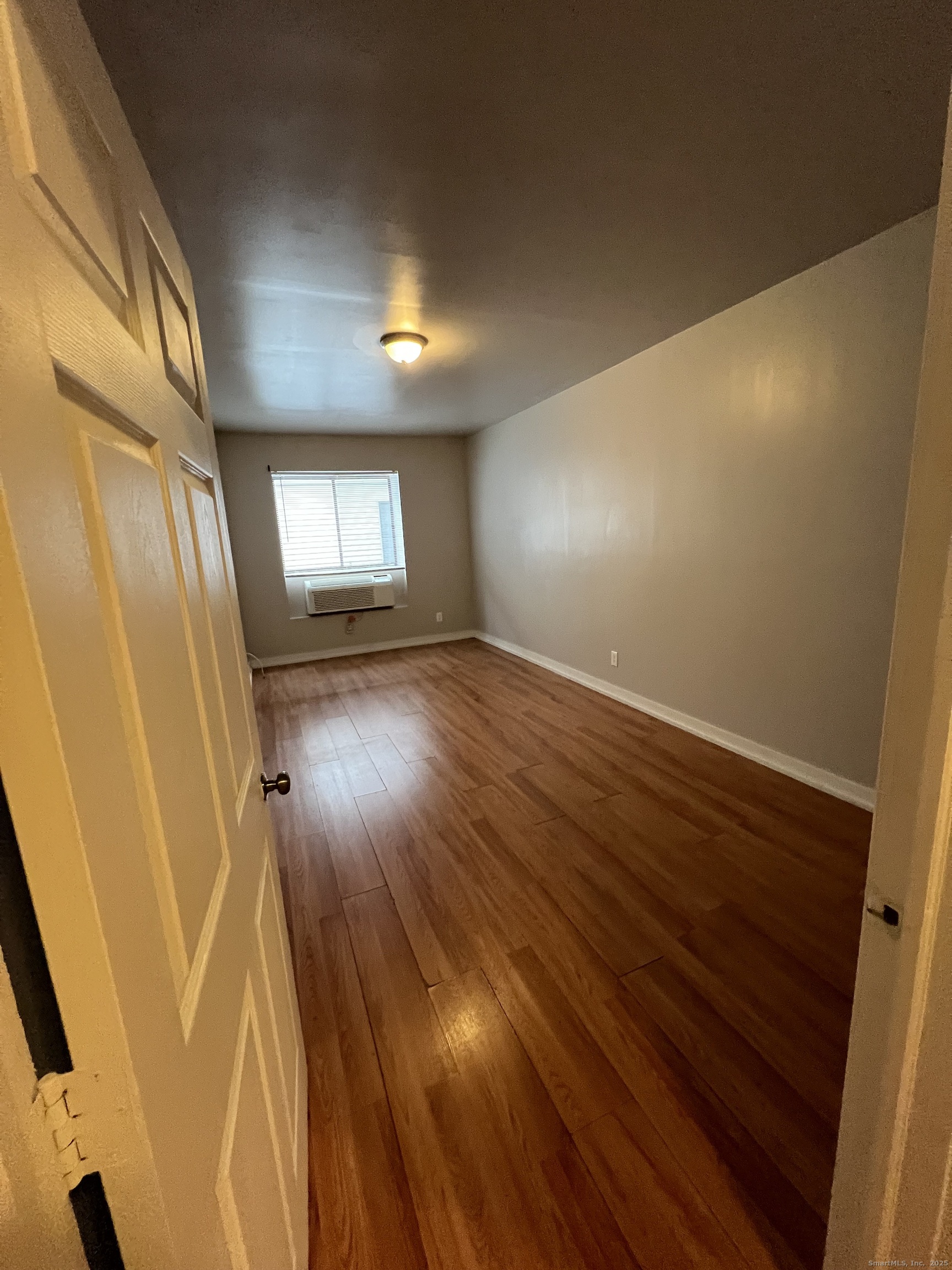 385 Putnam Avenue, Unit 26 Hamden, CT 06517 - Photo 5 of 11 an empty room with wooden floor and windows