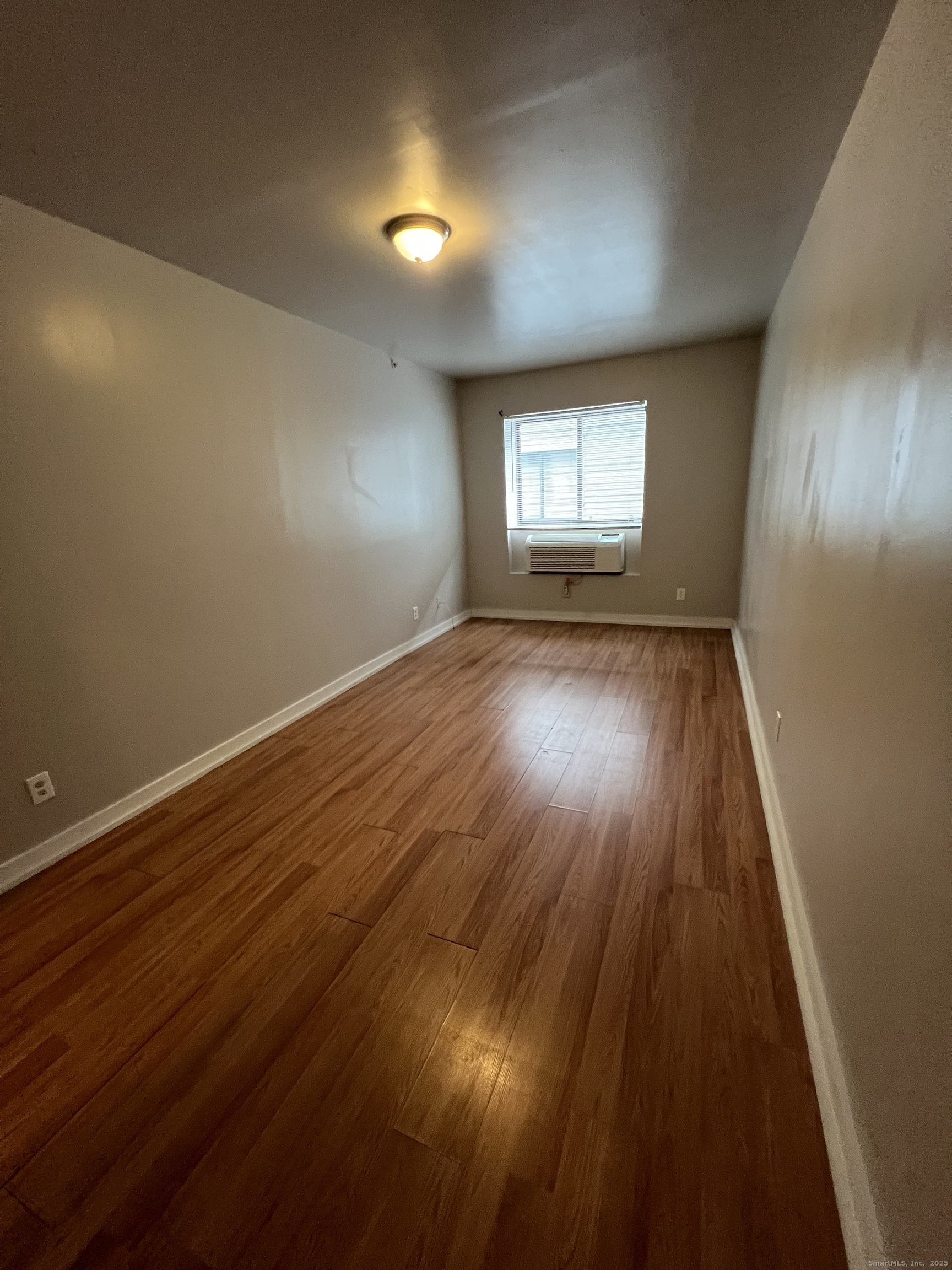 385 Putnam Avenue, Unit 26 Hamden, CT 06517 - Photo 6 of 11 an empty room with wooden floor and windows