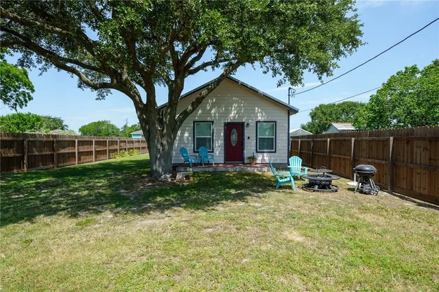 a view of backyard with table and chairs and a large tree