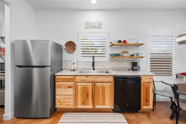 a kitchen with stainless steel appliances granite countertop a sink and a refrigerator