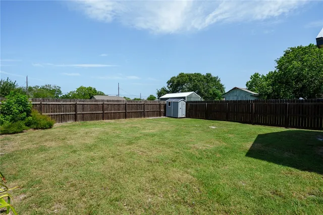a view of a backyard with large trees and wooden fence
