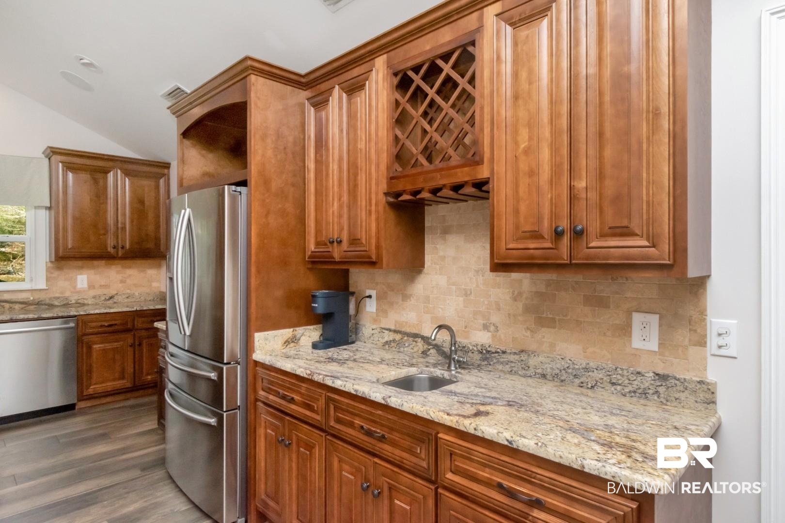 231 Rochester Road Mobile, AL 36608 - Photo 9 of 51 Kitchen featuring wood finish cabinetry, light stone counters, stainless steel appliances, lofted ceiling, and decorative backsplash