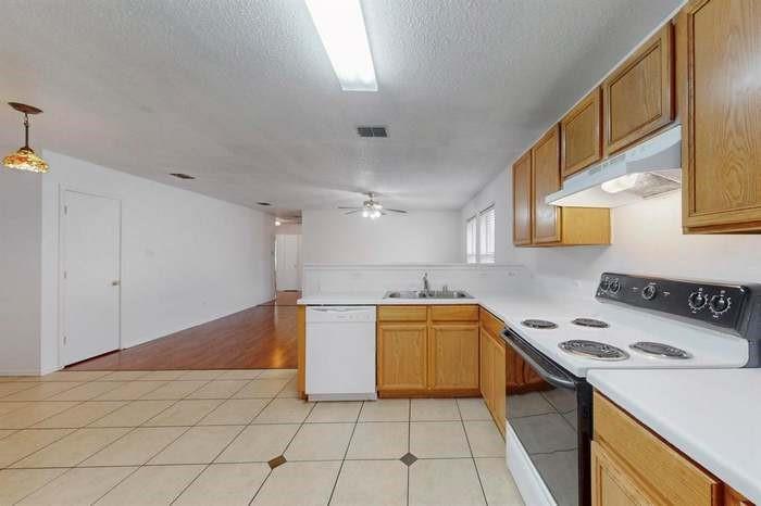 7515 Rice Lane Dallas, TX 75241 - Photo 13 of 15 Kitchen with electric range oven, light countertops, white dishwasher, a peninsula, and a ceiling fan