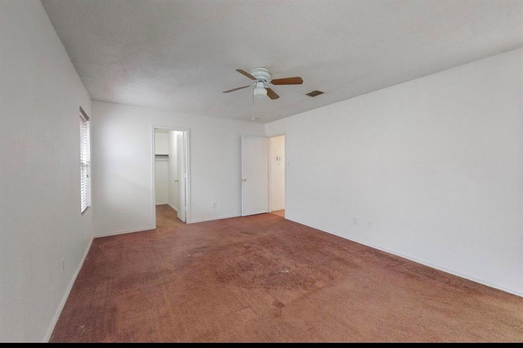 7515 Rice Lane Dallas, TX 75241 - Photo 5 of 15 Unfurnished bedroom with a spacious closet, carpet, and a ceiling fan