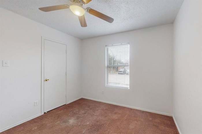7515 Rice Lane Dallas, TX 75241 - Photo 9 of 15 Spare room with dark colored carpet, a textured ceiling, and ceiling fan