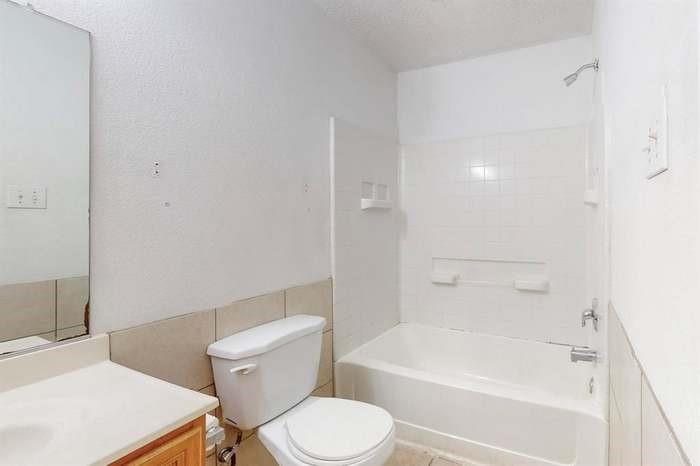 7515 Rice Lane Dallas, TX 75241 - Photo 10 of 15 Bathroom with vanity, bathing tub / shower combination, and tile walls