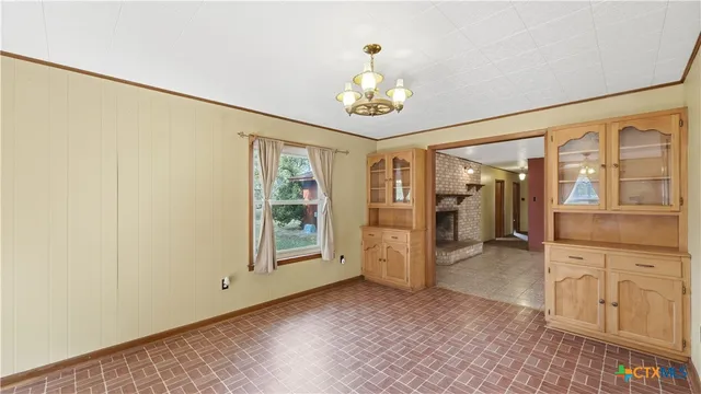 an empty room with chandelier fan and windows