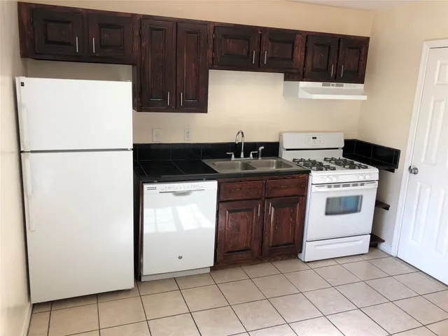 a white refrigerator freezer and a stove sitting inside of a kitchen with granite countertop cabinets