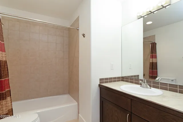 a bathroom with a granite countertop sink and a bathtub