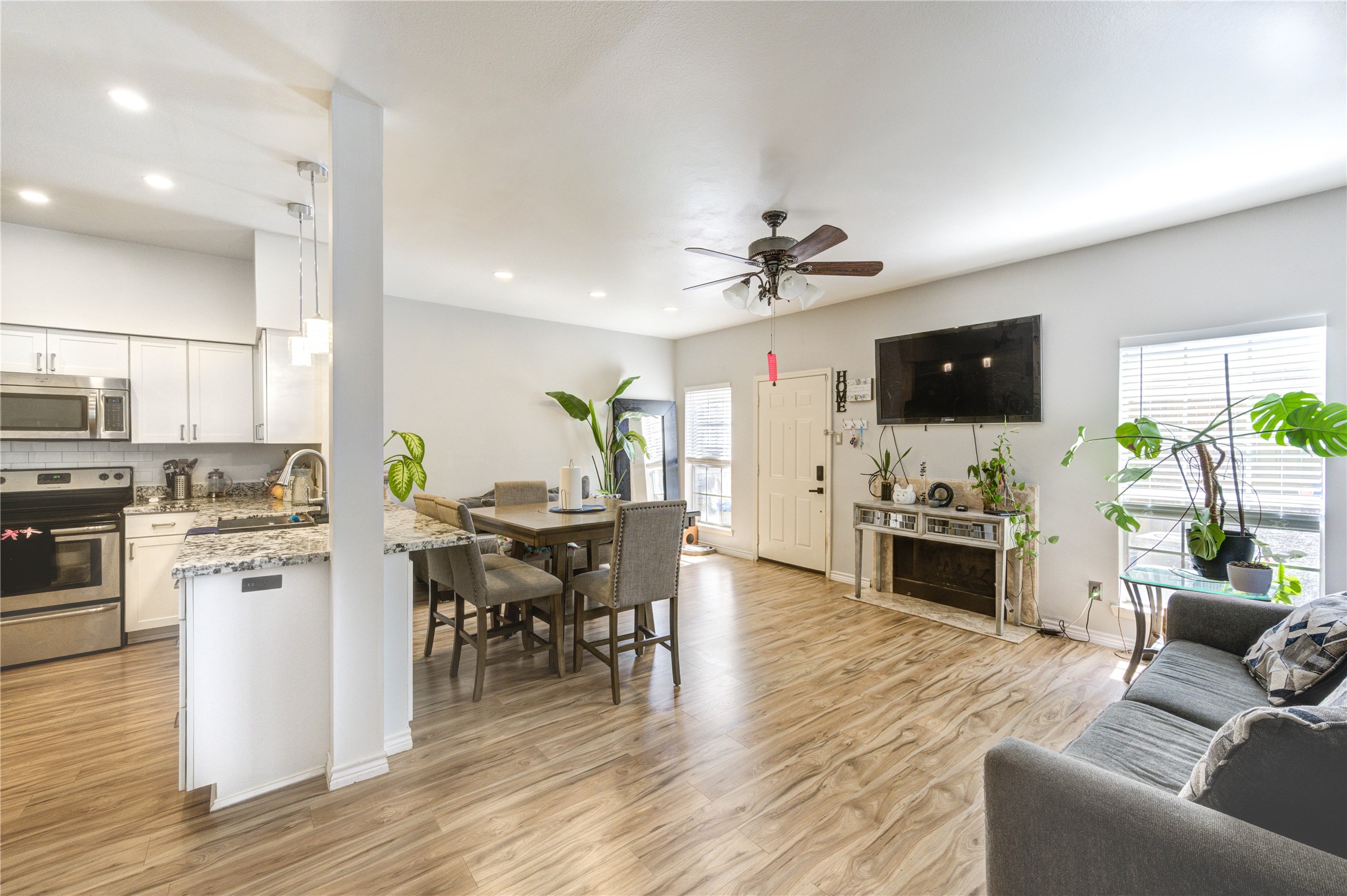 a living room with furniture a dining table and kitchen view with wooden floor