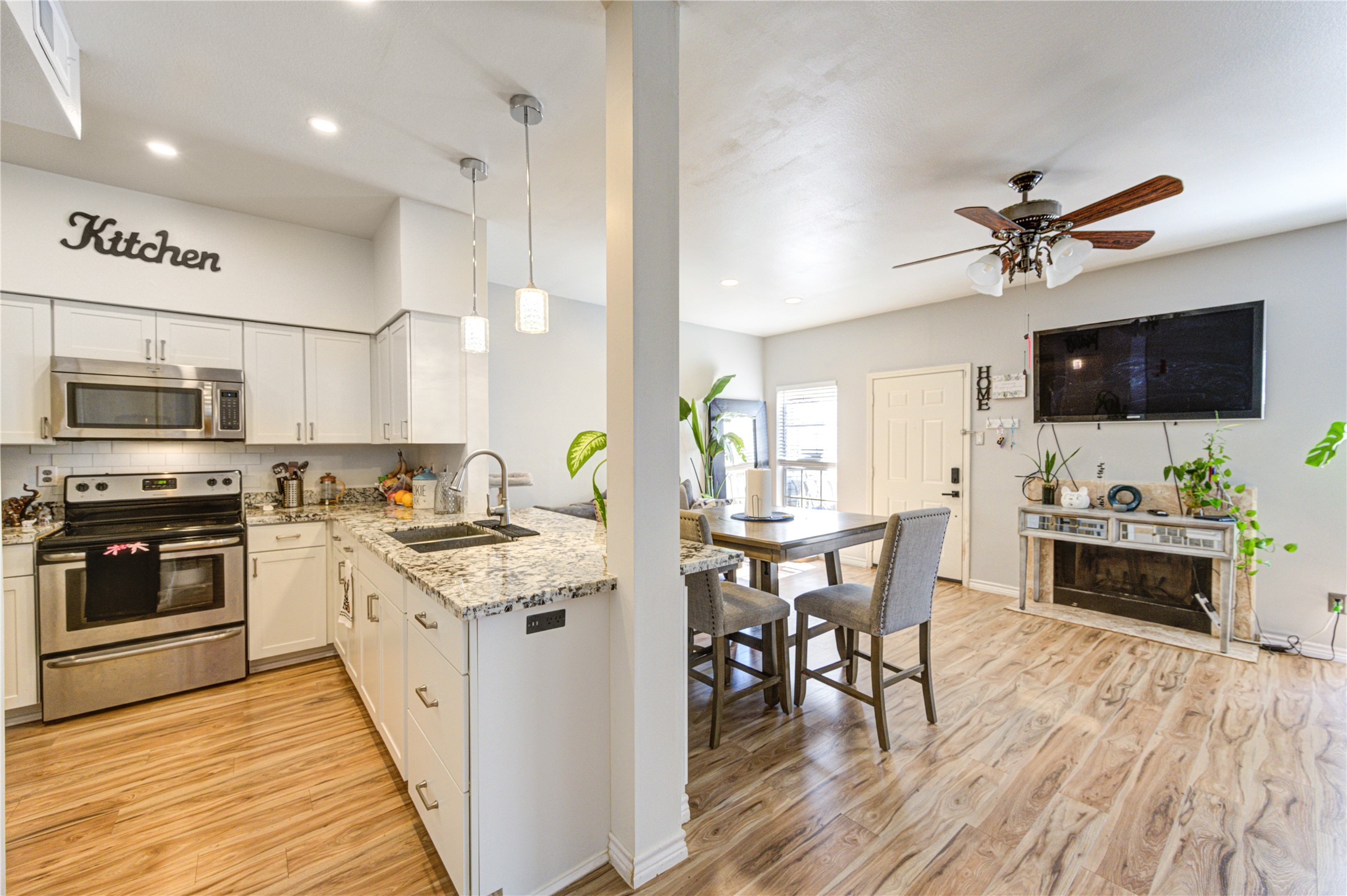 3800 Tanglewilde Street, Unit 803 Houston, TX 77063 - Photo 8 of 36 a kitchen with stainless steel appliances a stove a sink a microwave a dining table and chairs with wooden floor