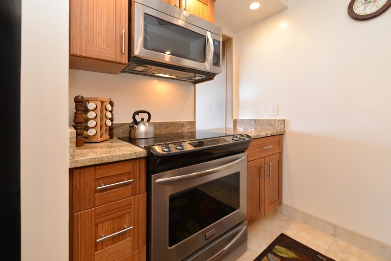 3741 Lower Honoapiilani Road, Unit 301 Lahaina, HI 96761 - Photo 7 of 18 a kitchen with granite countertop a stove top oven microwave and cabinets