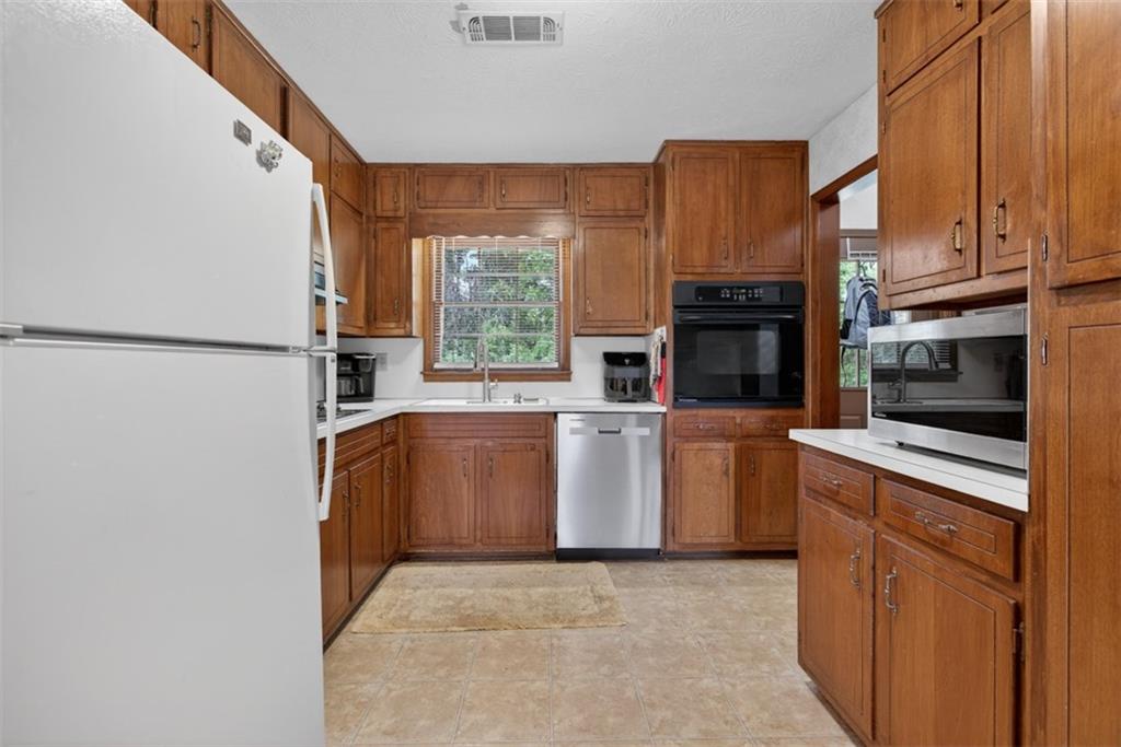 1177 Charlie Lane Southwest Lilburn, GA 30047 - Photo 20 of 49 a kitchen with stainless steel appliances a refrigerator sink and cabinets