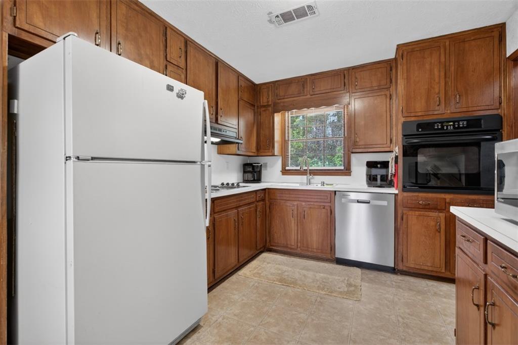 1177 Charlie Lane Southwest Lilburn, GA 30047 - Photo 24 of 49 a kitchen with cabinets a refrigerator and a stove