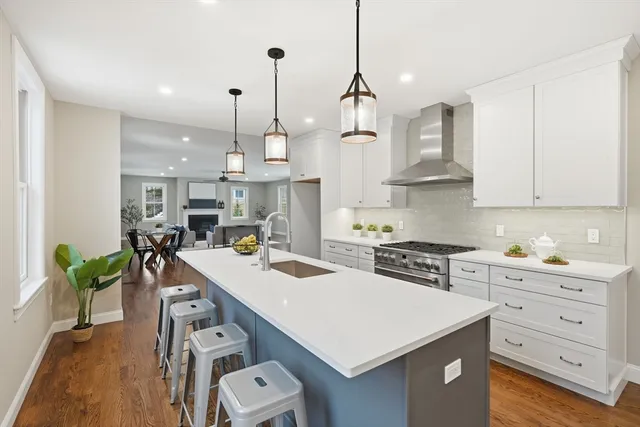 a kitchen with kitchen island a stove a table a sink a refrigerator and cabinets