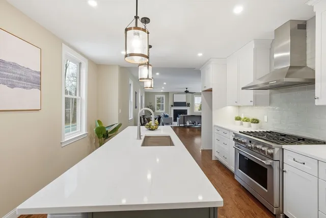a kitchen with stainless steel appliances granite countertop a sink a stove and a wooden floors
