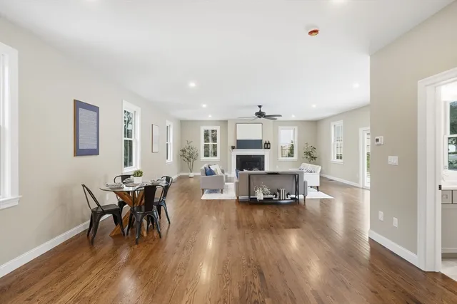 a living room with furniture and a dining table with wooden floor