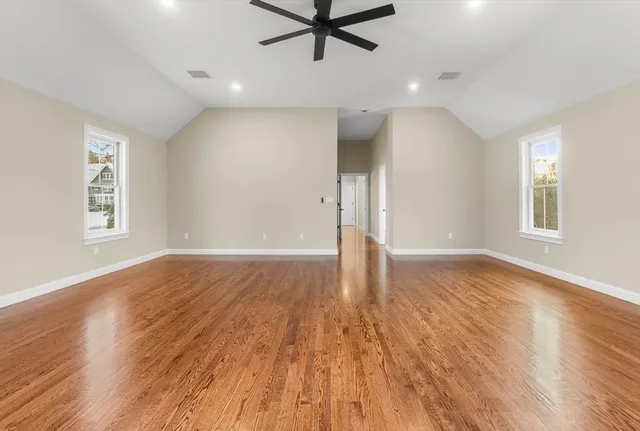 a view of empty room with wooden floor and fan