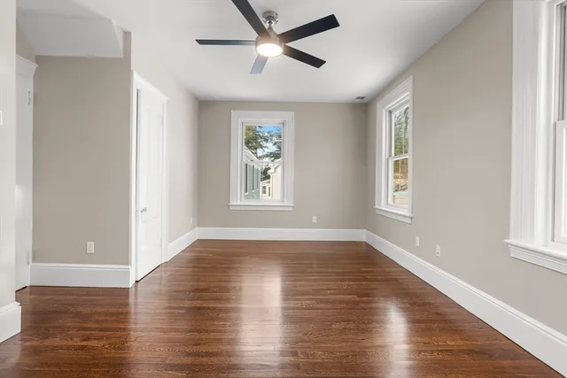 a view of empty room with wooden floor and fan