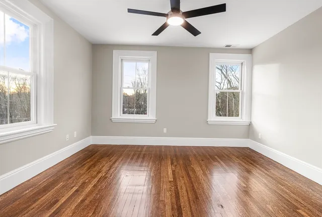 a view of empty room with wooden floor and fan