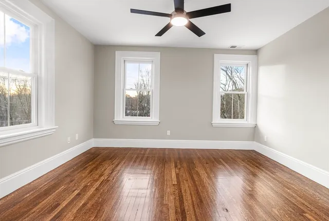 a view of empty room with wooden floor and fan