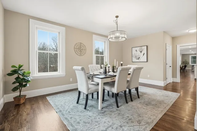 a dining room with wooden floor a chandelier a wooden table and chairs