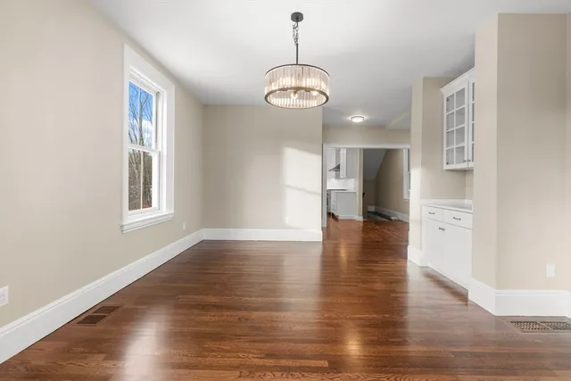 a view of an empty room with wooden floor and windows