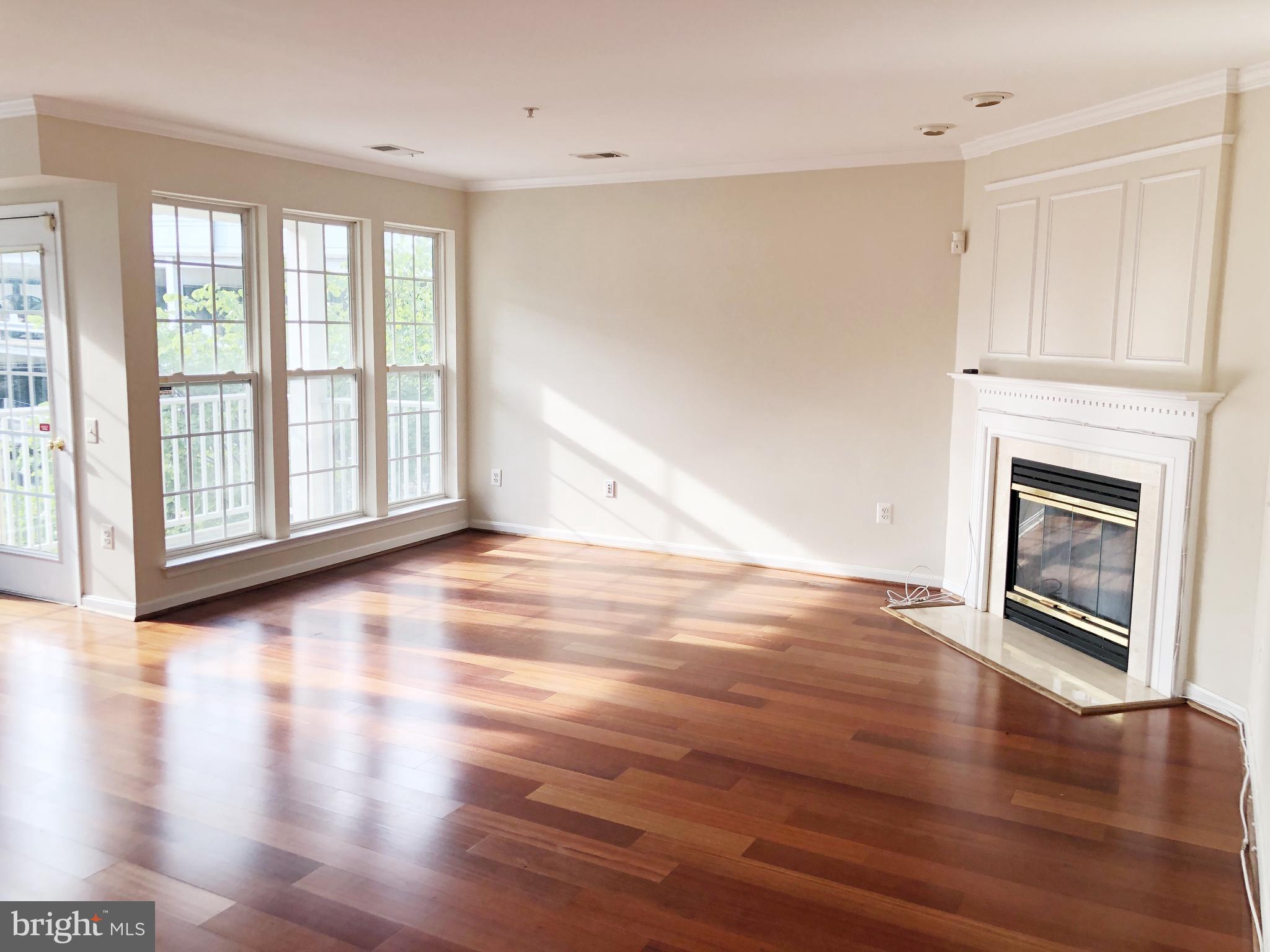 a view of an empty room with window wooden floor and fire place