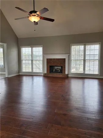 an empty room with wooden floor fireplace and windows