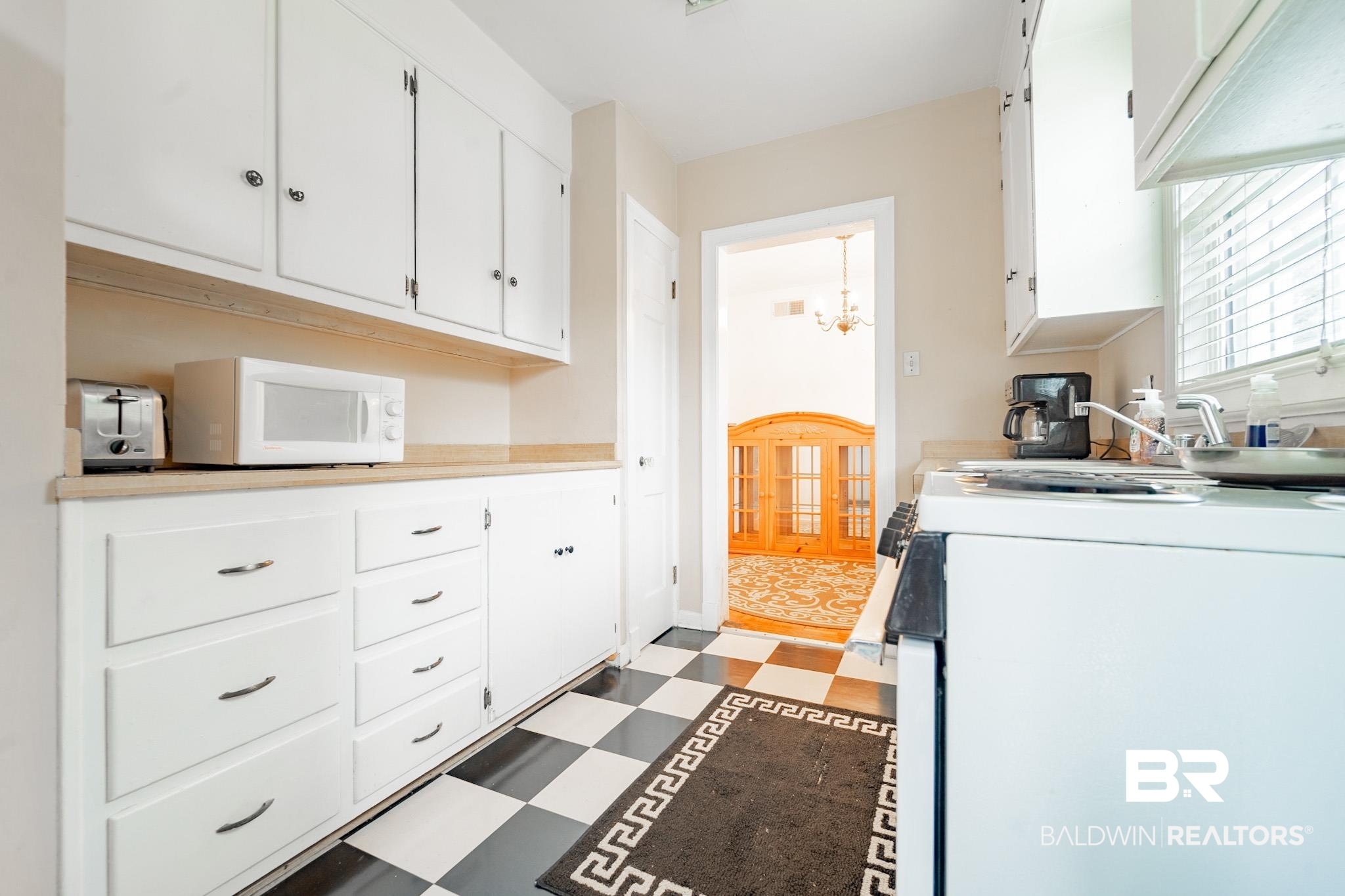 Kitchen featuring a notable chandelier, white cabinetry, and white appliances