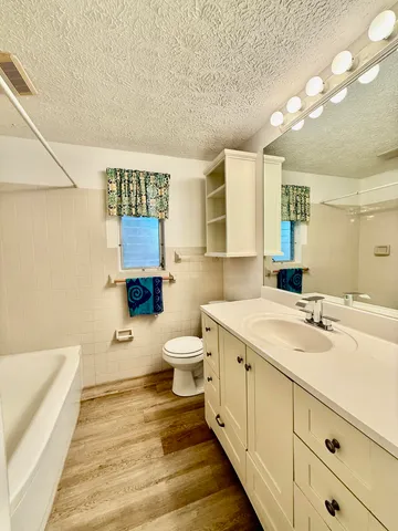 a spacious bathroom with a double vanity sink a mirror and a toilet