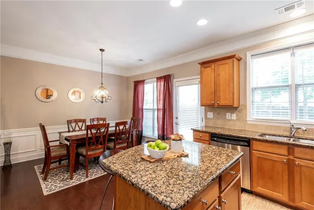 a kitchen with granite countertop a stove a sink a dining table and chairs with wooden floor