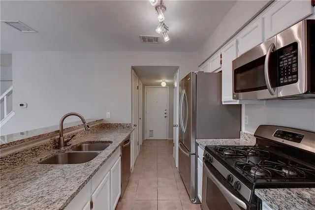 a kitchen with stainless steel appliances granite countertop a sink and a stove top oven with wooden floor