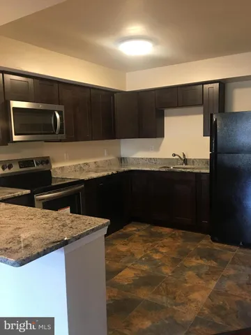 a kitchen with kitchen island sink and refrigerator