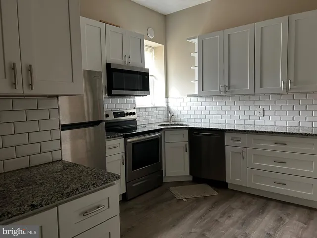 a kitchen with white cabinets and stainless steel appliances
