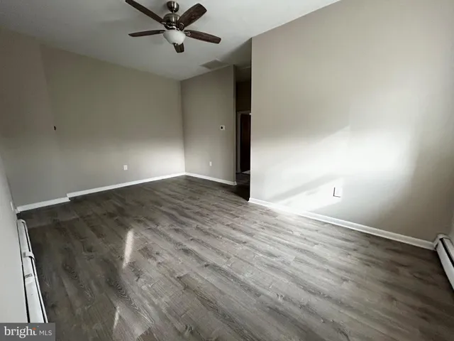 an empty room with wooden floor a ceiling fan and windows