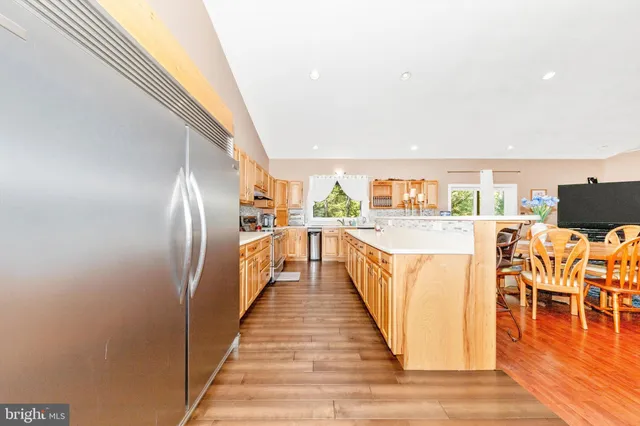 a kitchen with stainless steel appliances granite countertop a stove a sink and white cabinets with wooden floor
