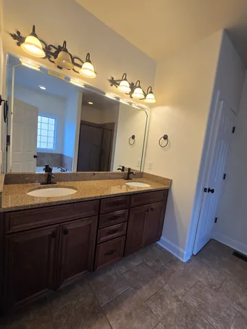 a bathroom with a granite countertop double vanity sink and a mirror