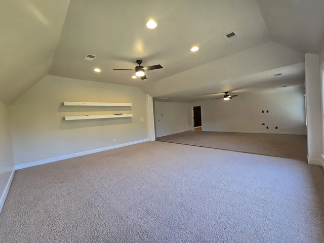 an empty room with a ceiling fan and windows