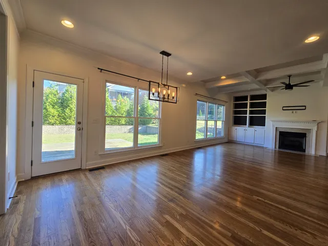 an empty room with wooden floor fireplace cabinet and windows