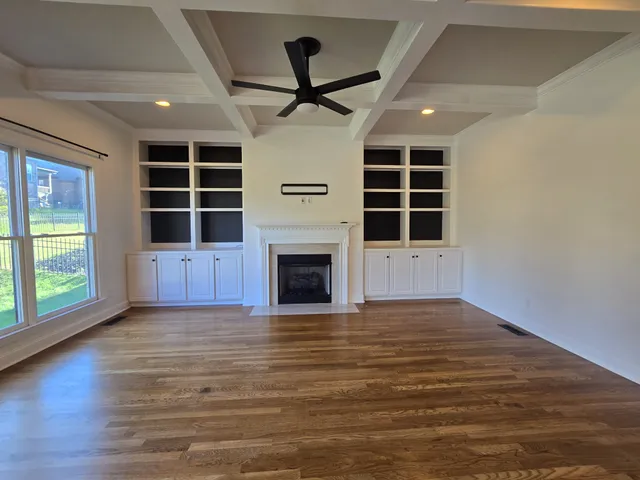 a view of an empty room with a window and kitchen view